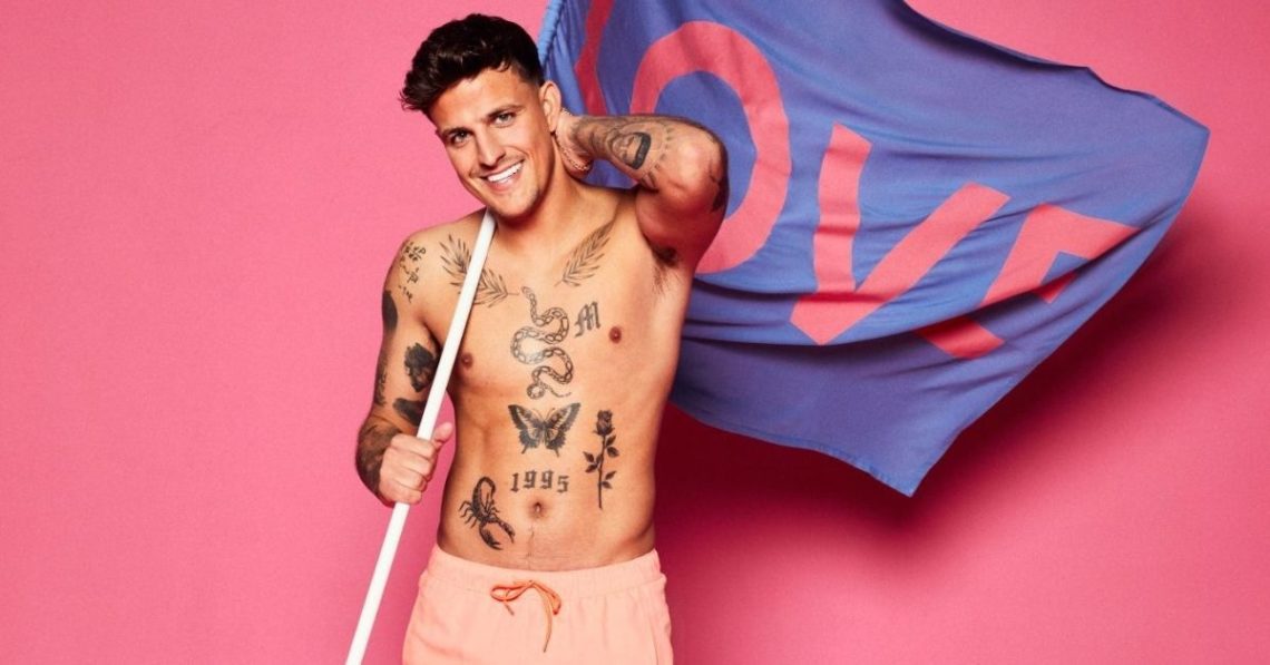 Luca Bish holds a flag with the word LOVE written on it shirtless