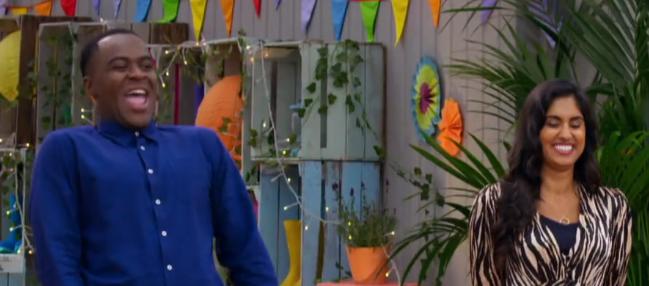 Liam Charles in blue top and Ravneet Gill in patterned dress laugh on Junior Bake Off.