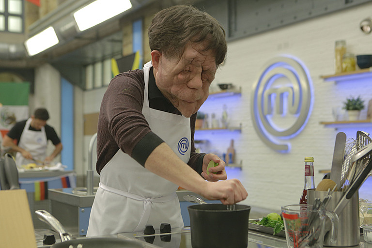 Adam Pearson squeezes lime into bowl using right hand while wearing white MasterChef apron.