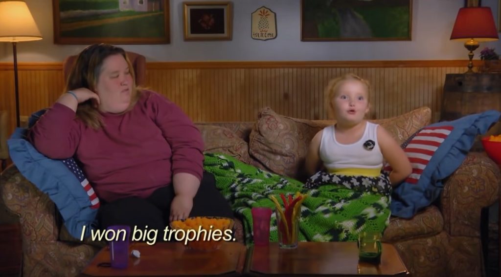 Honey Boo Boo or Alana Thompson sits on the couch next to Mama June on Toddlers and Tiaras