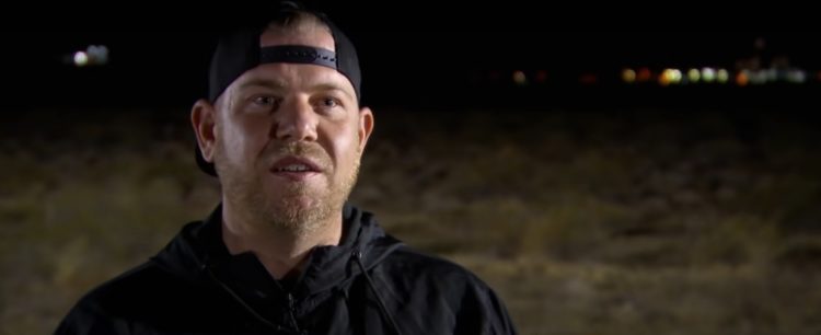 Ryan Fellows in Street Outlaws interview, he stares at the camera and wears a black jacket and black cap