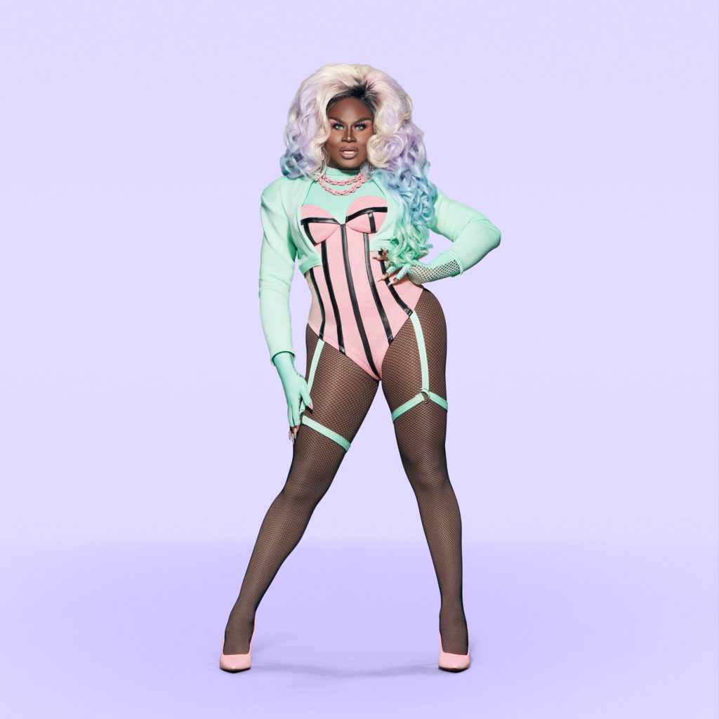 Drag Queen LaLa Ri wears a racy pink and green ensemble consisting of a tight corset and suspenders in a Promo for RuPaul Drag Race Season 13