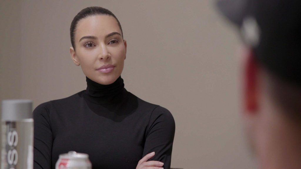 Kim Kardashian wears a black top with her arms crossed.