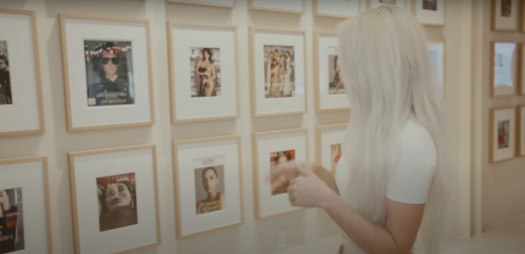 Kim Kardashian looks at her framed magazine covers on the wall of her SKNN offices