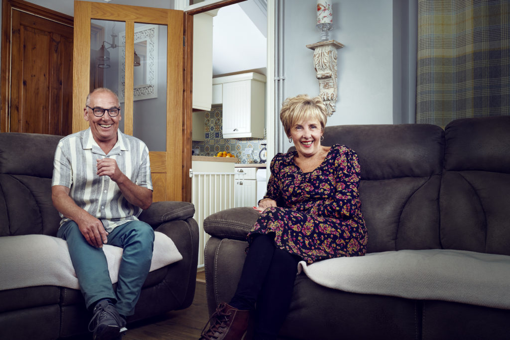 Dave and Shirley smile on sofa in their Caerphilly home.