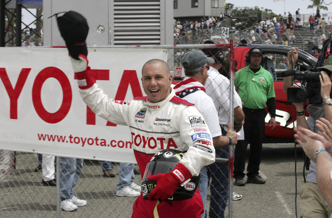 Dave Mirra celebrates holding hat in air smiling in the victory circle after winning the 31st Annual Toyota Pro/Celebrity Race