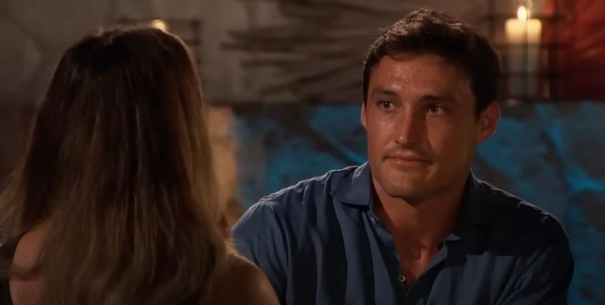 Tino speaks to Rachel on The Bachelorette facing the camera wearing a blue shirt