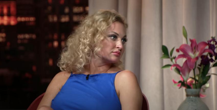 Natalie Mordovtseva looks over to her left wearing a high neck cobalt blue dress
