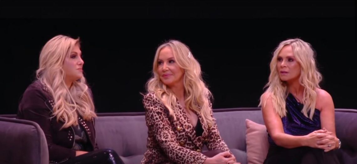 The Real Housewives of Orange County cast sit facing one another on a sofa at a BravoCon panel