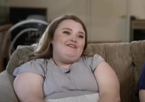Honey Boo Boo waring a grey t-shirt as she seats on a couch and smiles talking about her boyfriend, Dralin