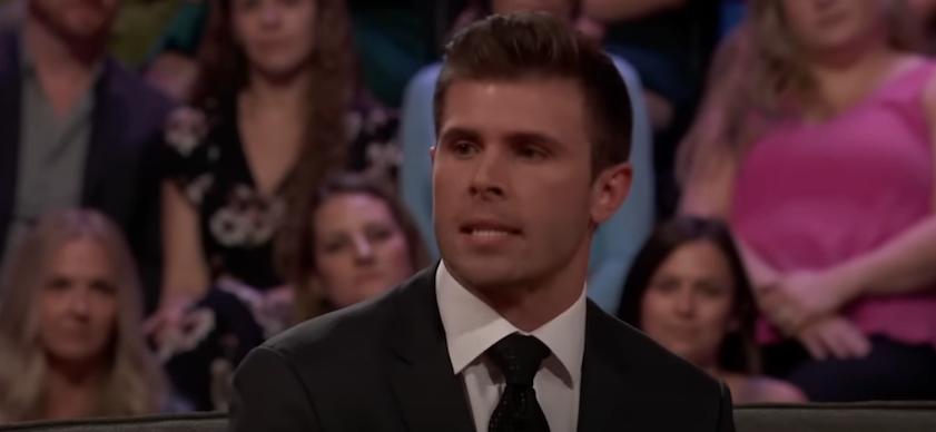 Zach Shallcross speaks on The Bachelorette sofa wearing suit and tie