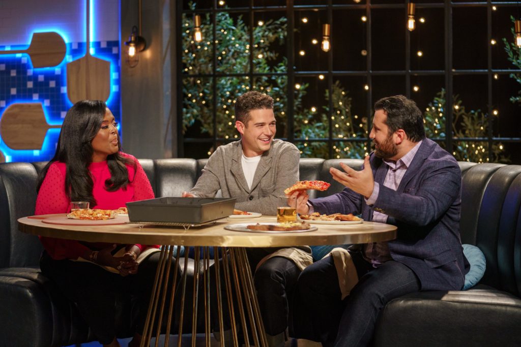 Millie Peartree, Wells Adams, and Daniele Uditi sit around a table looking at one another on Best in Dough