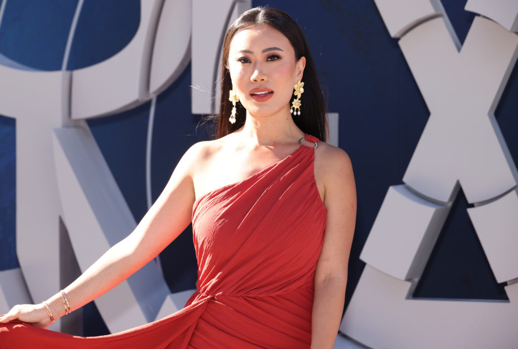 Kelly Mi Li wears a one shoulder red dress and holds it out to the side as she attends the World Premiere Of Netflix's "The Gray Man" - Arrivals