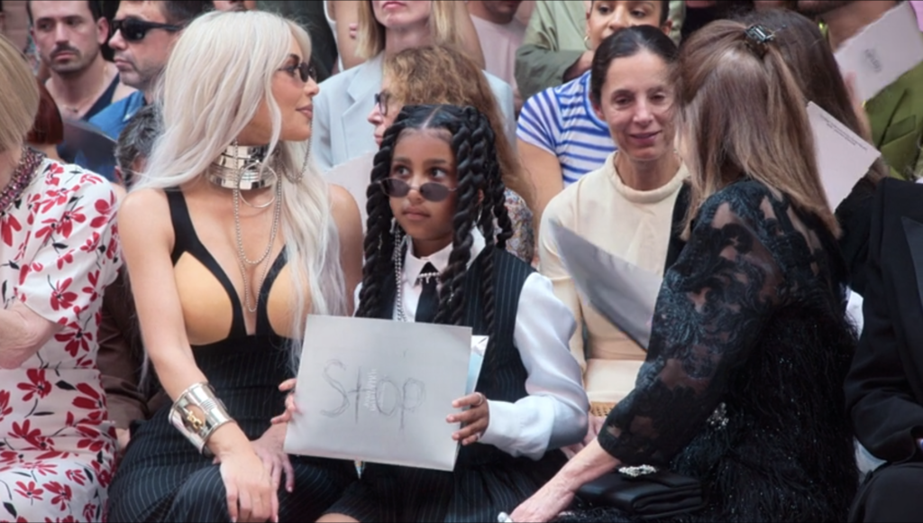 North West holds a 'stop' sign at Jean Paul Gautier fashion show in Paris