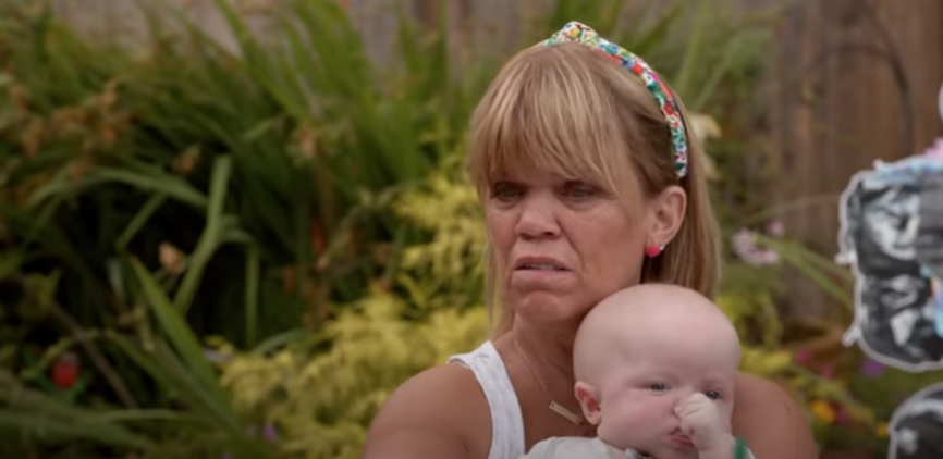 Amy Roloff holds baby in garden swearing headband and white vest top