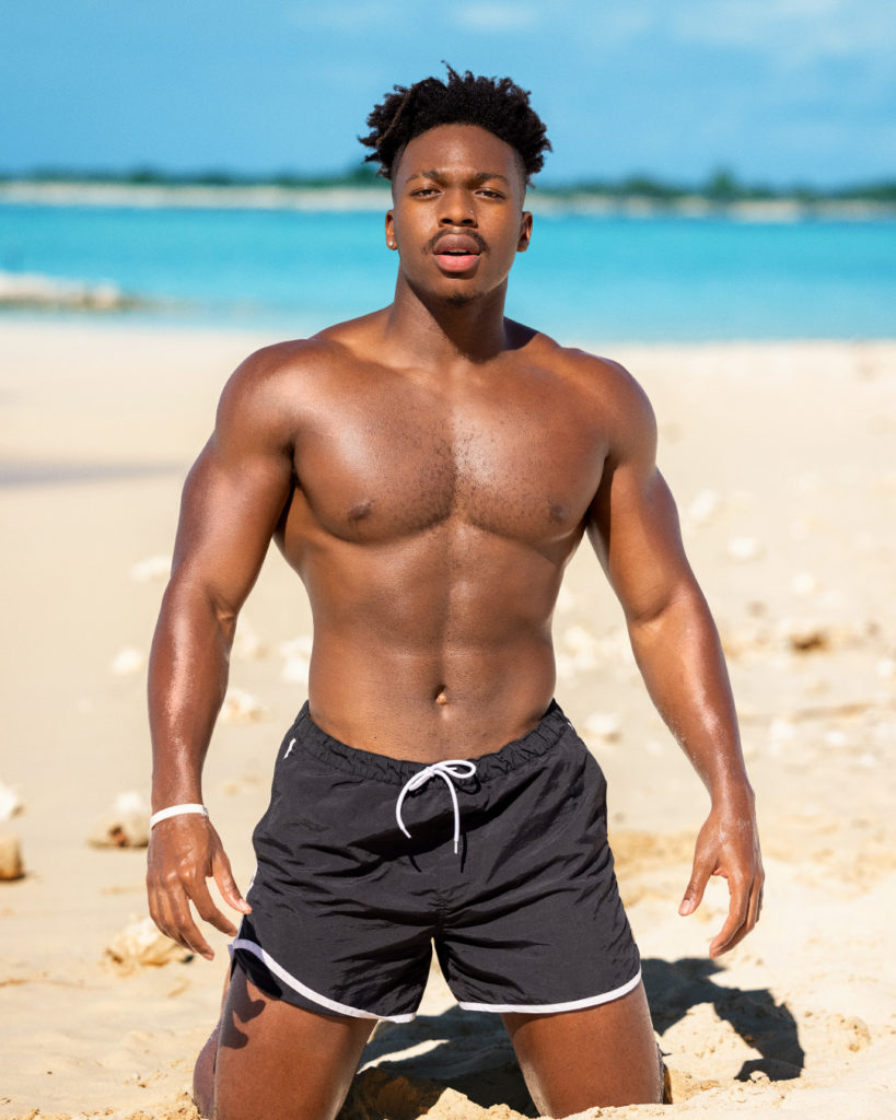 James from Too Hot To Handle poses on beach wearing swim shorts for show's promo