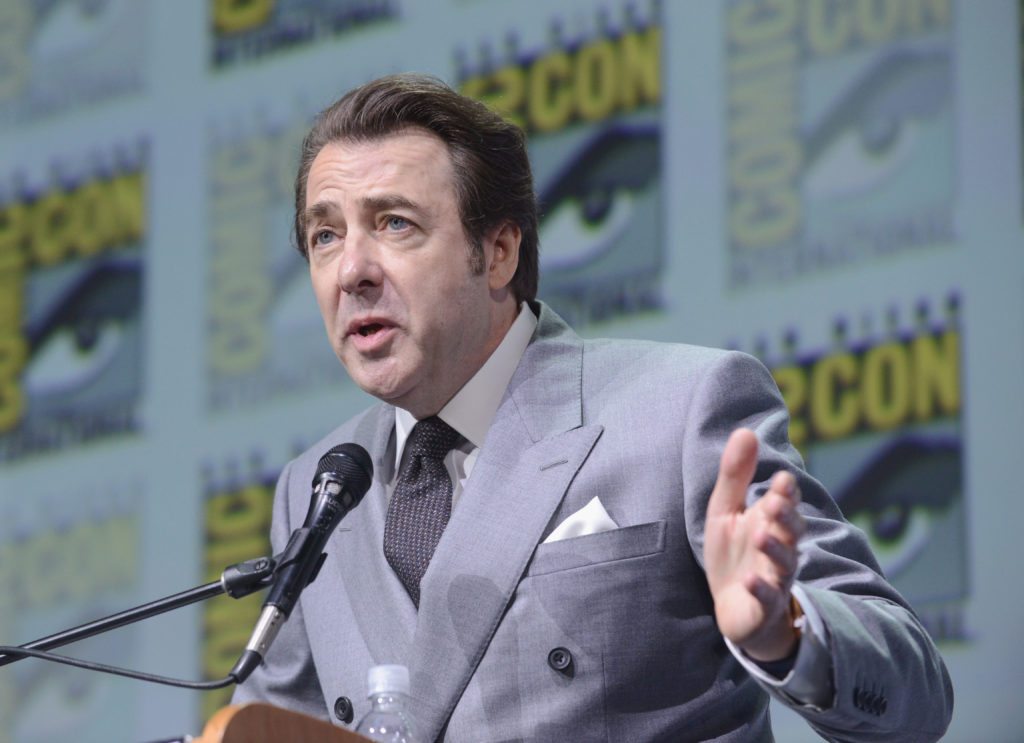 Jonathan Ross speaks into microphone at Comic-Con International 2017 event wearing grey suit and tie