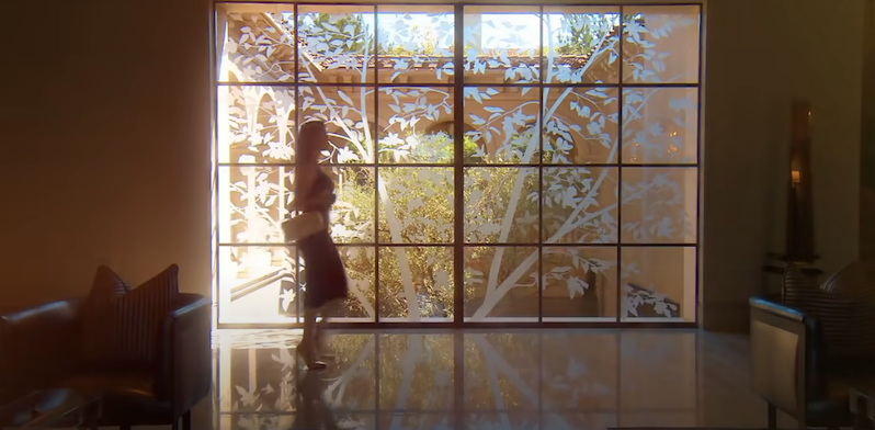 Heather Dubrow walks past her etched window on RHOC wearing a black dress