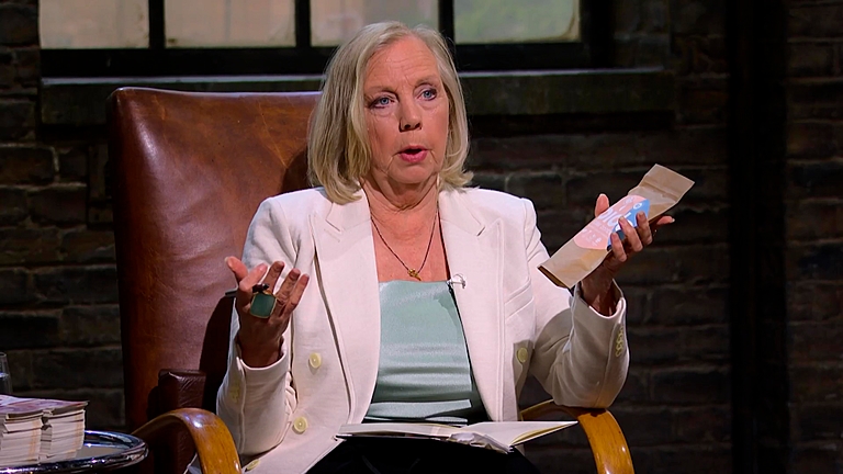 Deborah Meaden sits in her chair on Dragons' Den  holding a product