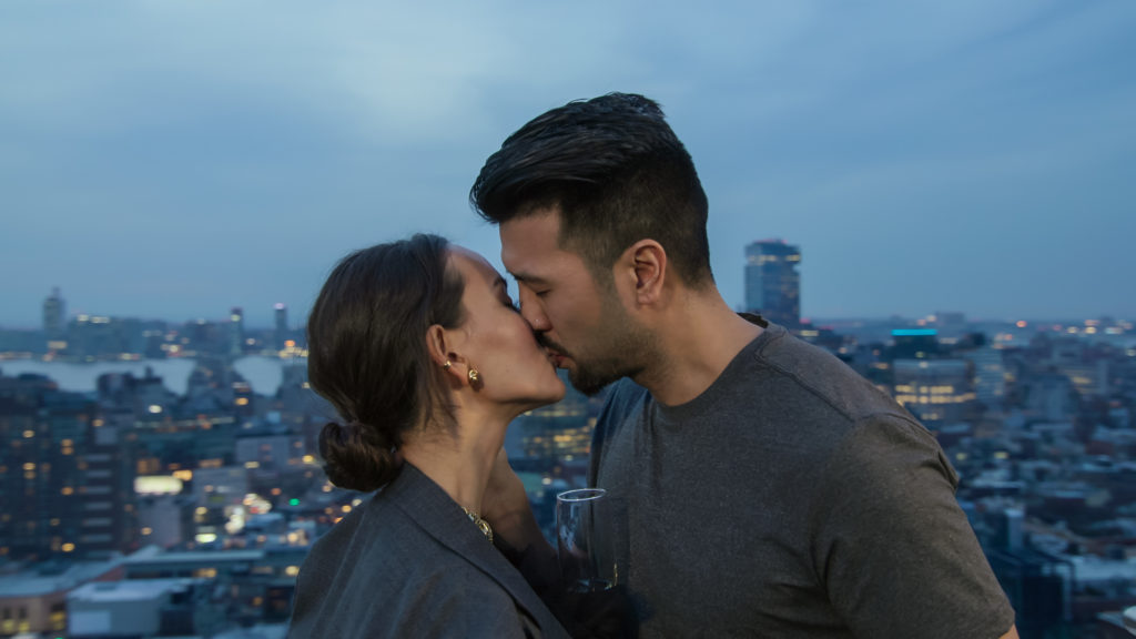 Richard and Vika kiss with city skyline in background
