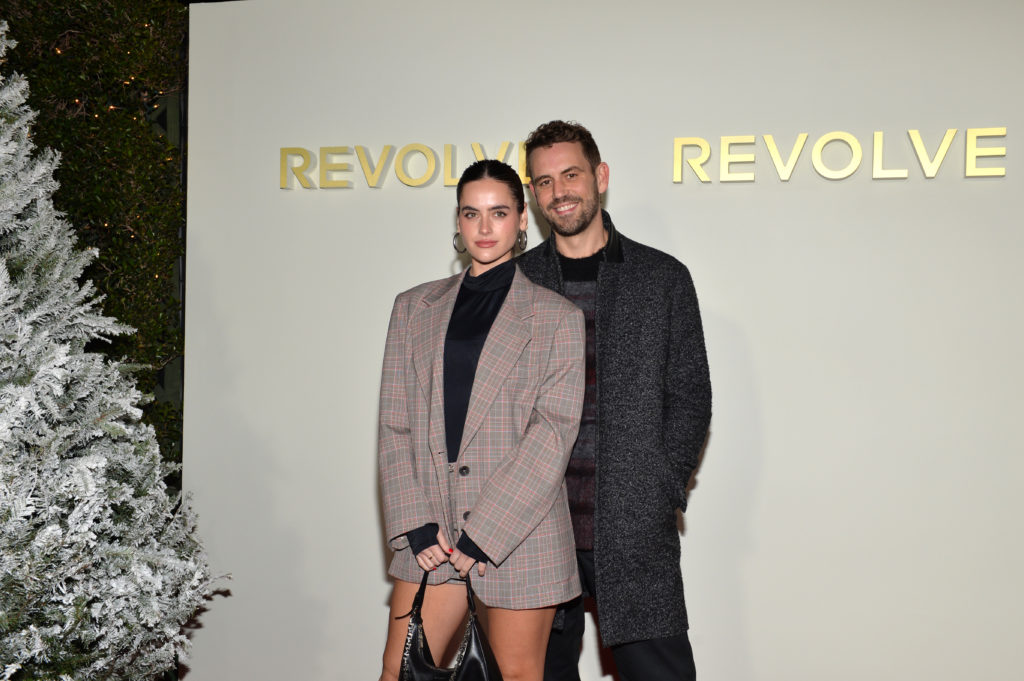 Natalie Joy and Nick Viall pose together at REVOLVE event, Natalie stands in front of Nick wearing blazer dress