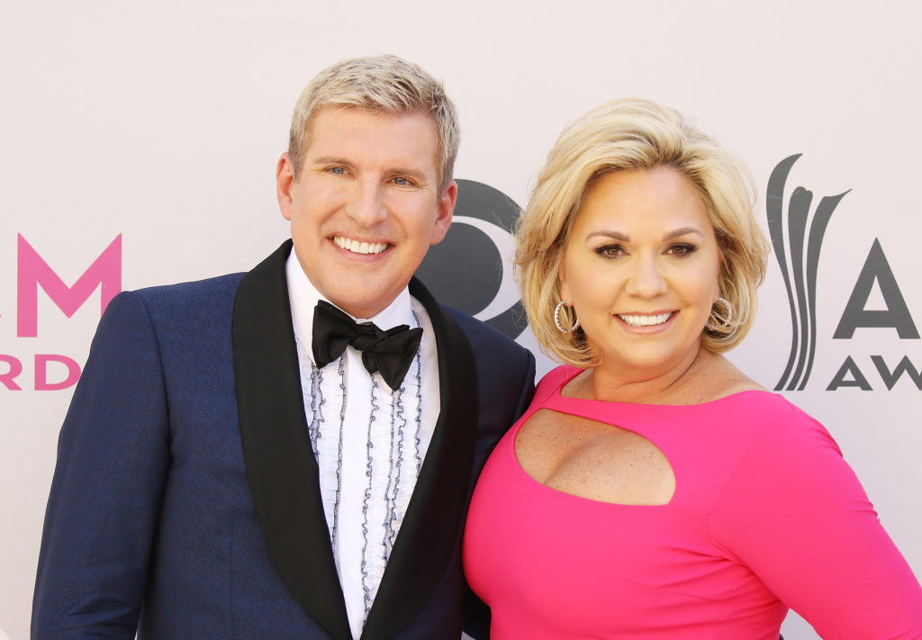 Todd and Julie Chrisley smile for camera. Todd is wearing suit and tie and Julie wears pink gown at 52nd Academy Of Country Music Awards