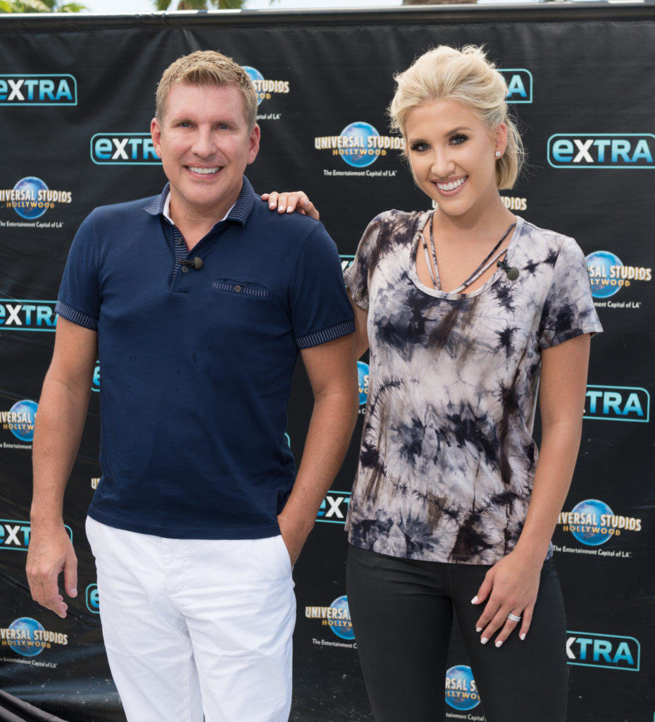 Todd And Savannah Chrisley pose on red carpet wearing casual top and jeans smiling