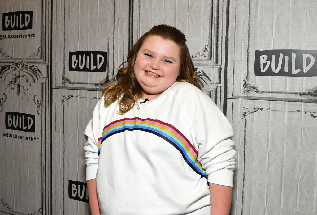 Honey Boo Boo smiles wearing white jumper with rainbow on it