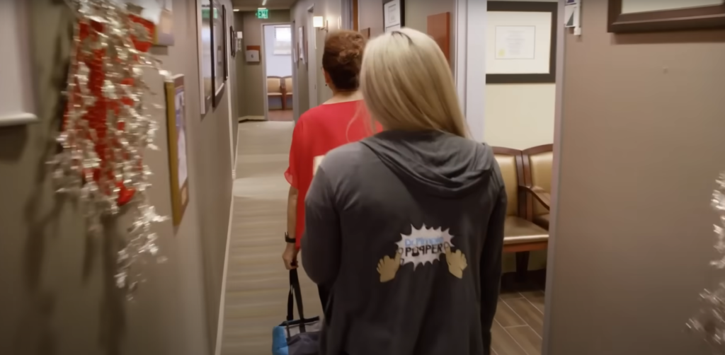 Two women walking down hallway of Dr Pimple Popper's office 