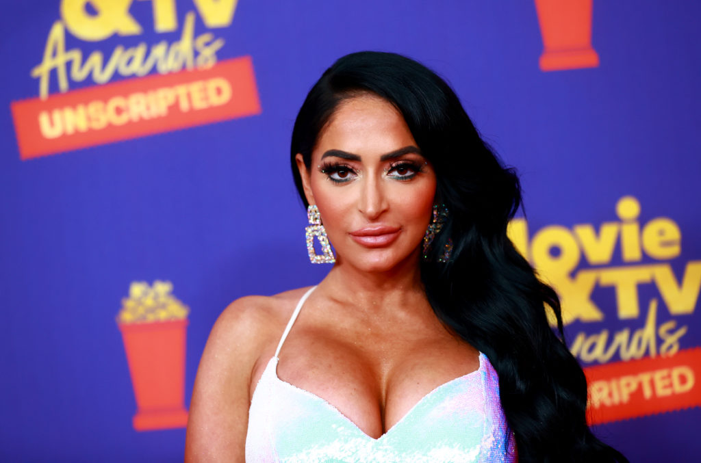 Angelina Pivarnick attends 2021 MTV Movie & TV Awards: UNSCRIPTED wearing white strappy dress and brown hair pushed to one side and diamond earrings
