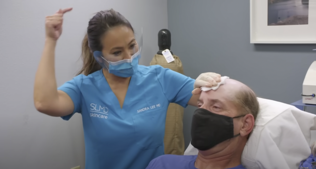 Dr Pimple Popper with her hand over a patients head