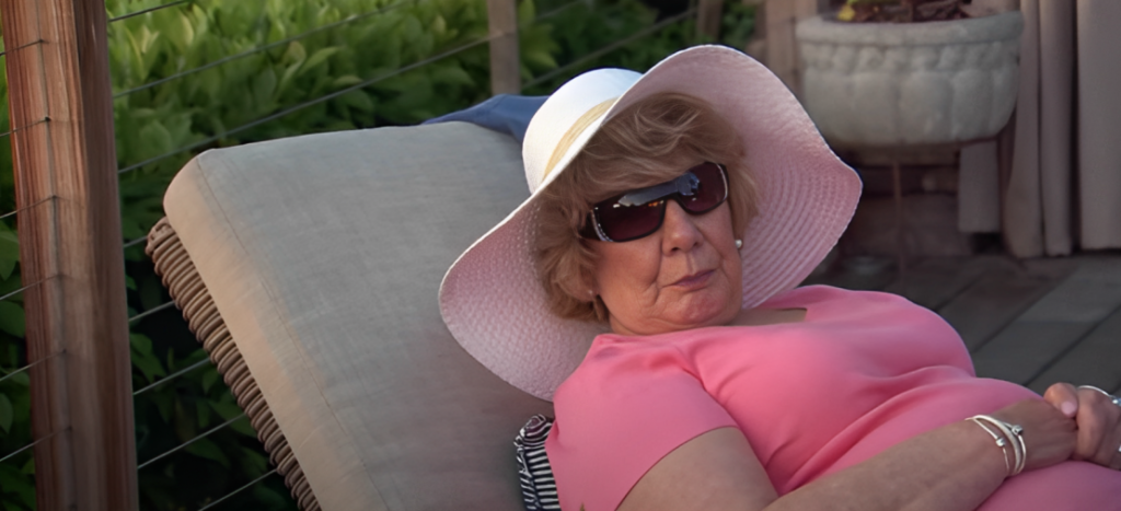 Nanny Faye Chrisley wearing hat and sunglasses and pink top laying on lounger