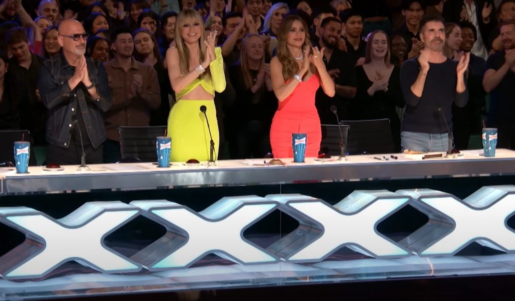 (L-R) Howie Mandel, Heidi Klum, Sofia Vergara, Simon Cowell clapping on their feet at America's Got Talent judges table