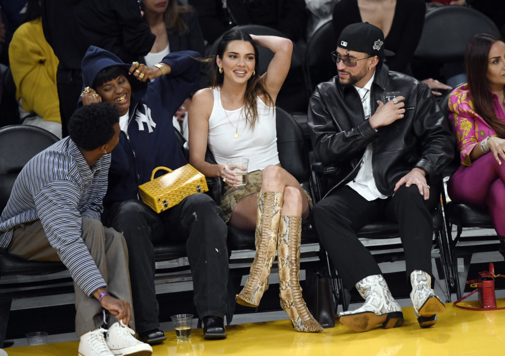 Kendall Jenner at The Los Angeles Lakers Game sitting next to Bad Bunny wearing white top, skirt and snake skin pattern boots