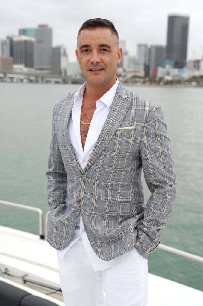 Nick poses in suit jack aboard yacht
