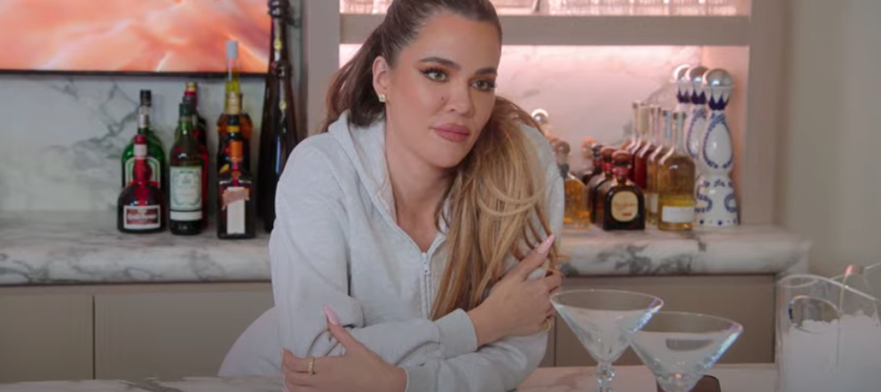 Khloé Kardashian leans elbows on kitchen counter wearing loungewear
