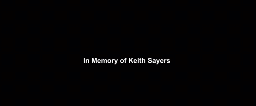 Screenshot of the words 'In Memory of Keith Sayers' reads on screen during Buddy Games