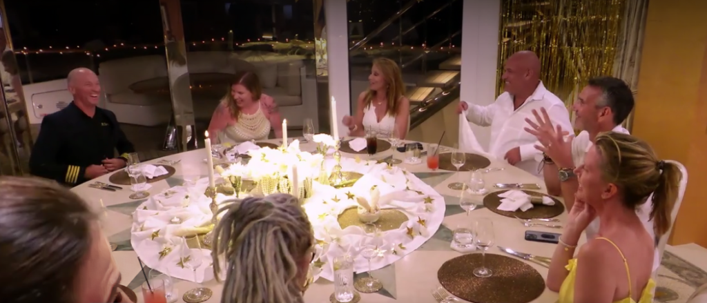 Jill Zarin and Below Deck guests sit around large table smiling.